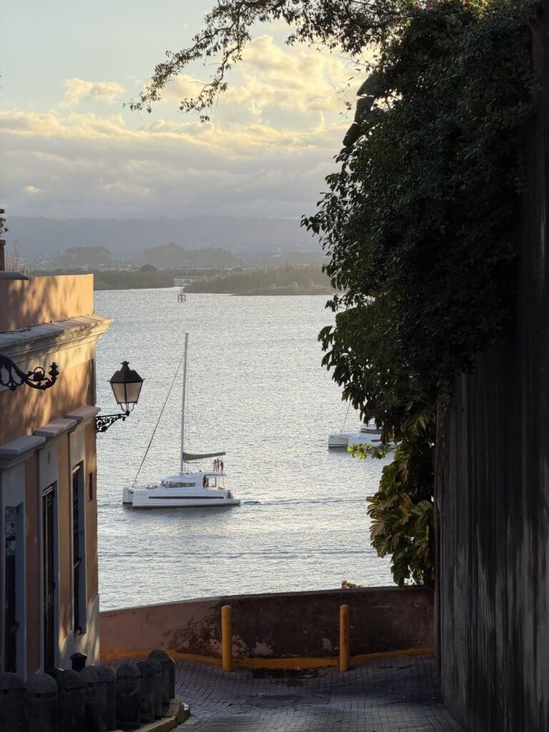 Narrow Old San Juan street opening toward the waterfront and a sailboat