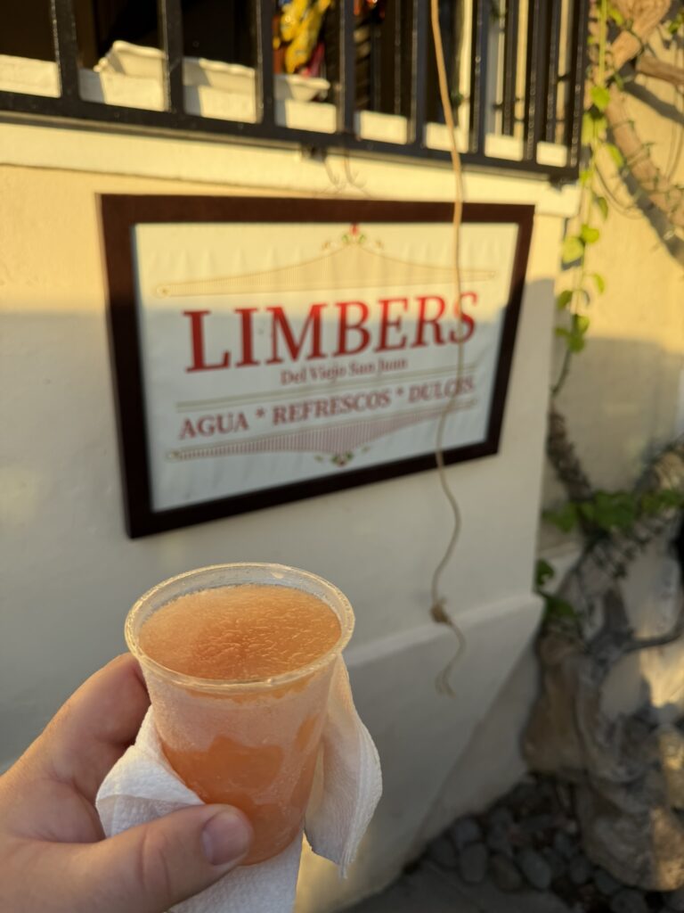 Cup of limber held beneath the Limbers sign in Old San Juan